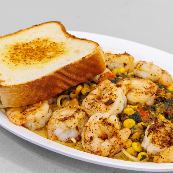 A'Nets Katch shrimp and pasta dish with corn, vegetables, and a slice of toasted bread.