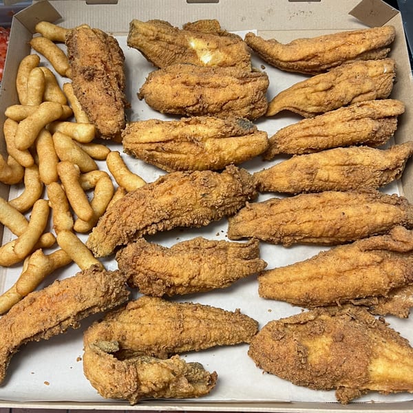A'Nets Katch fried fish fillets and hush puppies in a cardboard takeout box.