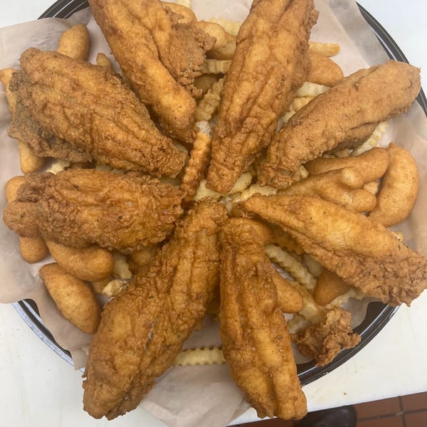 A'Nets Katch fried fish and hush puppies with crinkle-cut fries on a plate.