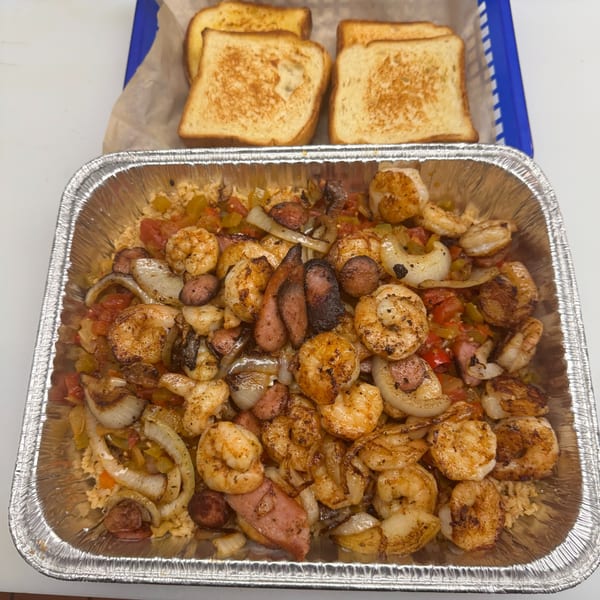 A'Nets Katch seafood platter with shrimp, sausage, onions, and peppers, served with toasted bread.