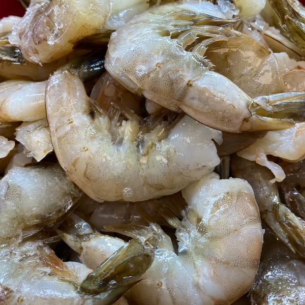 Close-up of fresh, raw, peeled shrimp with visible texture and some remaining shells.